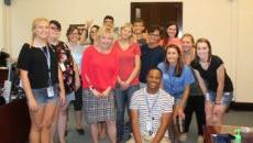 A group of SMWC students smiling with President Dottie King in her office.